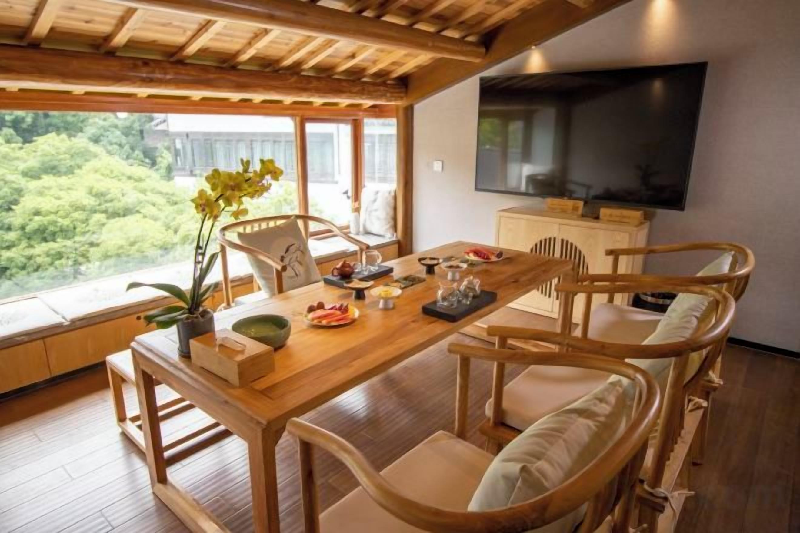 A dining area with a wooden table, chairs, and a television on the wall.