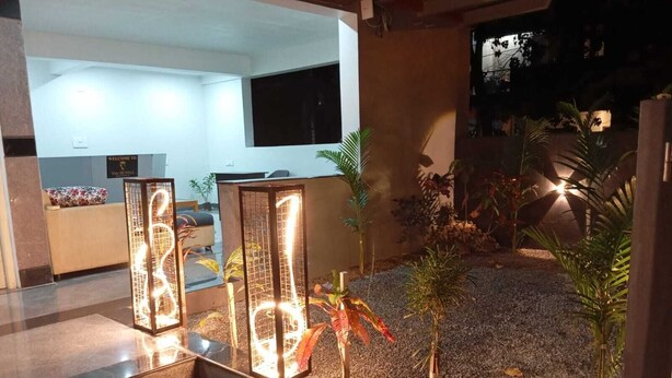 A reception area with a modern design, featuring a reception desk and a seating area. There are decorative light fixtures and potted plants in the foreground. - Vin Hotels & Service Apartments Manyata Tech Park (Bengaluru)
