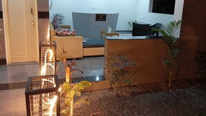 A modern living room with a sofa, a coffee table, and a TV. There are decorative plants and a small table with a vase. - Vin Hotels & Service Apartments Manyata Tech Park (Bengaluru)