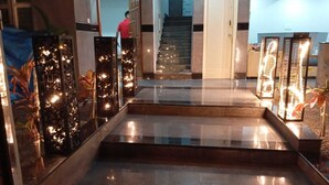 A modern hotel lobby with a glass staircase, a reception desk, and decorative pillars. - Vin Hotels & Service Apartments Manyata Tech Park (Bengaluru)