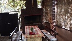 An outdoor patio with a checkered table, two benches, and a brick fireplace.