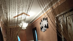 A hallway with a patterned carpet, a dining table with chairs, and a decorative hanging chain.