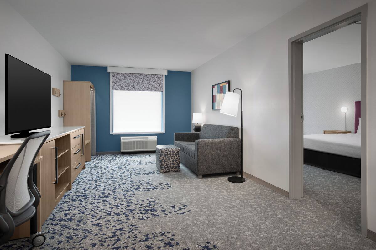 Ein modernes Hotelzimmer mit Schreibtisch, Stuhl und Bett.