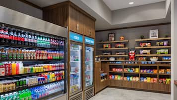Una sección de bebidas y aperitivos con bebidas refrigeradas y estantes llenos de tentempiés.