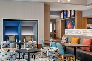 A modern hotel lobby with seating areas, a large wall with framed sports jerseys, and a visible staircase. - Tru by Hilton Houston Downtown Convention Center (Houston)