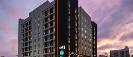 A multi-story hotel with a prominent 'HOME 2' sign, a modern architectural design, and a well-lit facade.