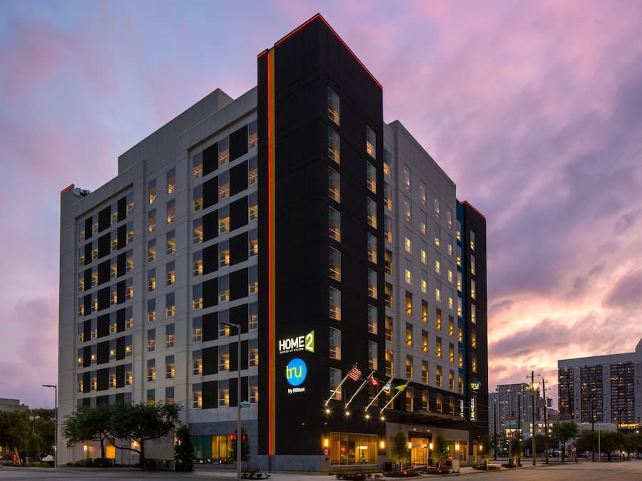 Um hotel de vários andares com uma placa de destaque 'HOME 2', design arquitetônico moderno e fachada bem iluminada.