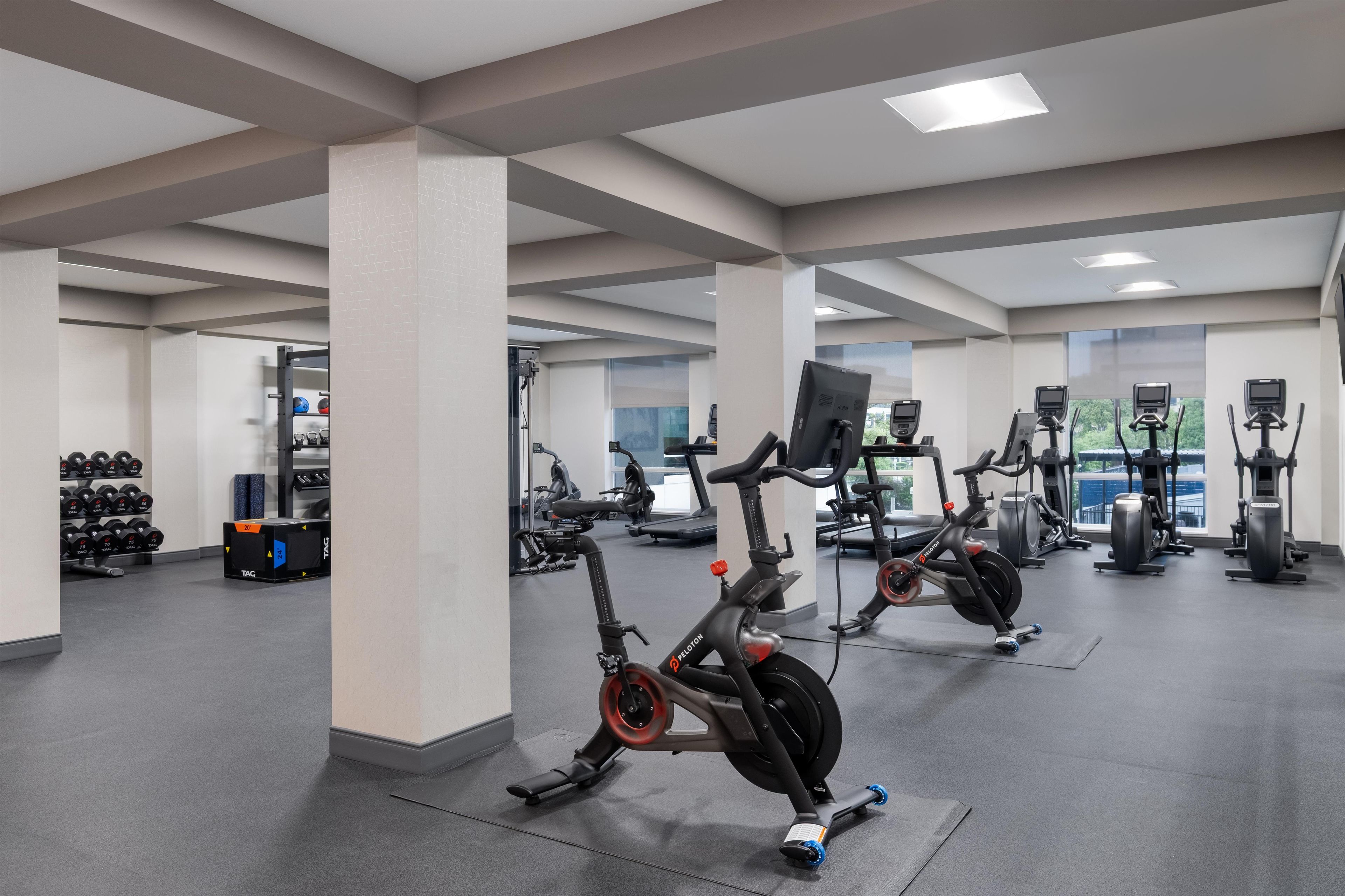 Een sportschool met diverse fitnessapparaten, waaronder hometrainers en loopbanden.
