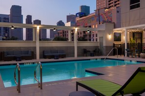 A rooftop pool with lounge chairs and a view of city buildings. - Tru by Hilton Houston Downtown Convention Center (Houston)