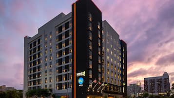 A multi-story hotel with a prominent "HOME 2" sign, multiple windows, and a well-lit entrance.