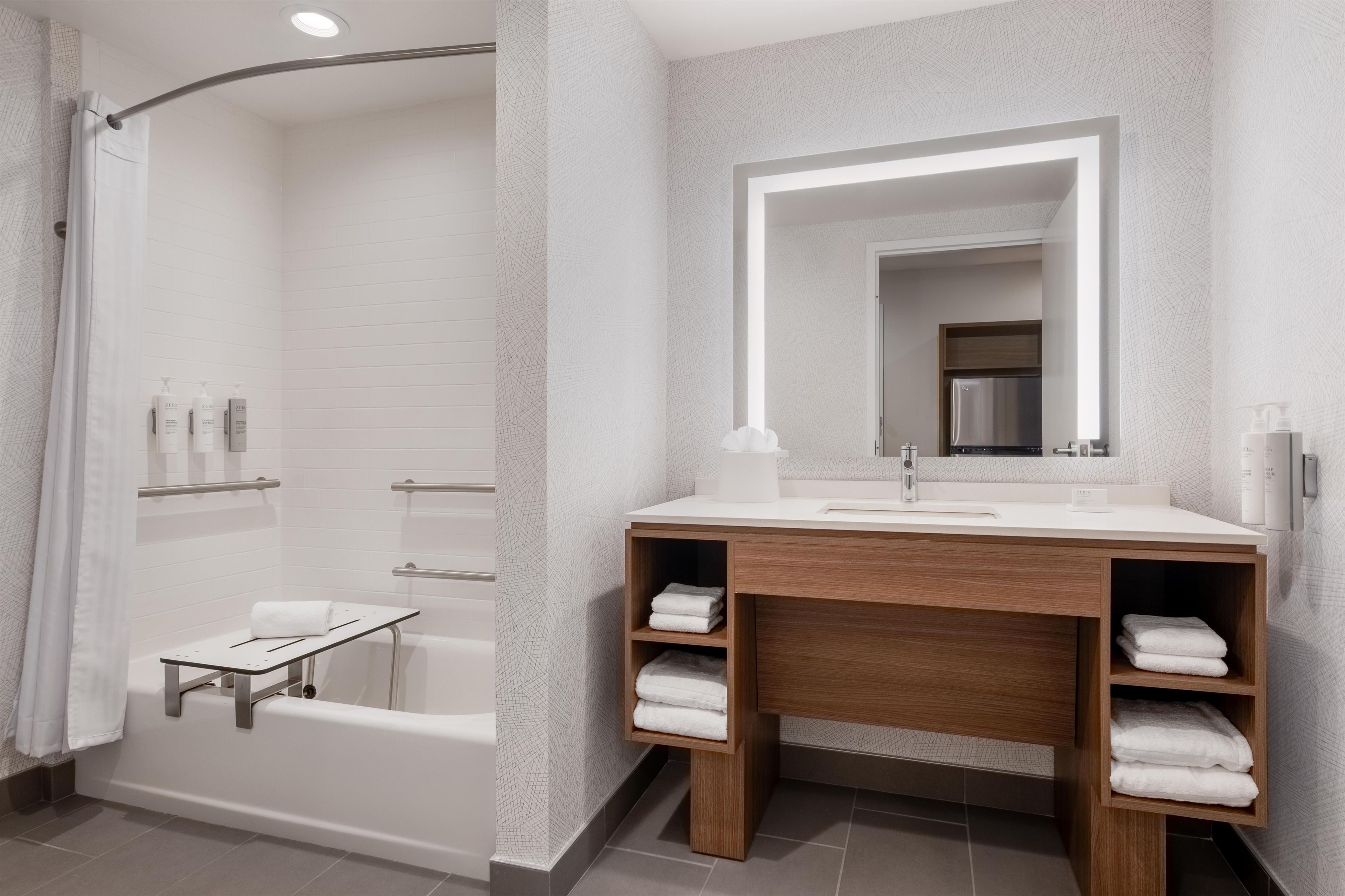 Un baño moderno con ducha, tocador con espejo y un perchero para toallas.