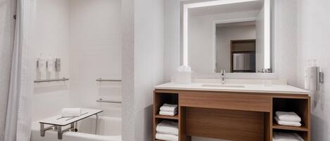 Un baño moderno con ducha, tocador con espejo y un perchero para toallas.