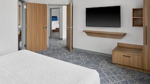 A hotel room with a bed, a TV mounted on the wall, a wooden cabinet, and a patterned carpet. - Hampton Inn by Hilton Lincoln Downtown (Lincoln)