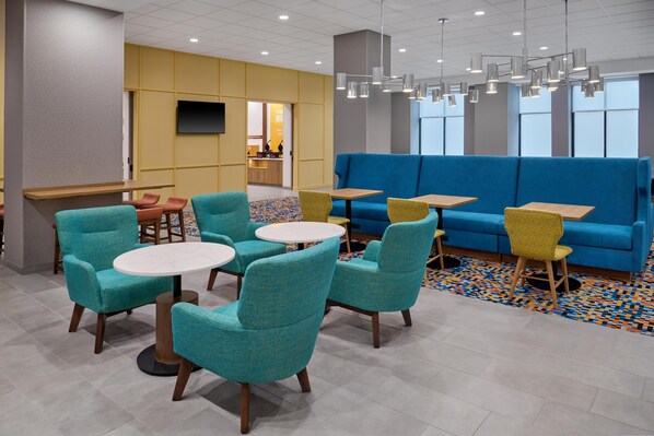 A modern lounge area with teal chairs, wooden tables, and a blue sofa. - Hampton Inn by Hilton Lincoln Downtown (Lincoln)
