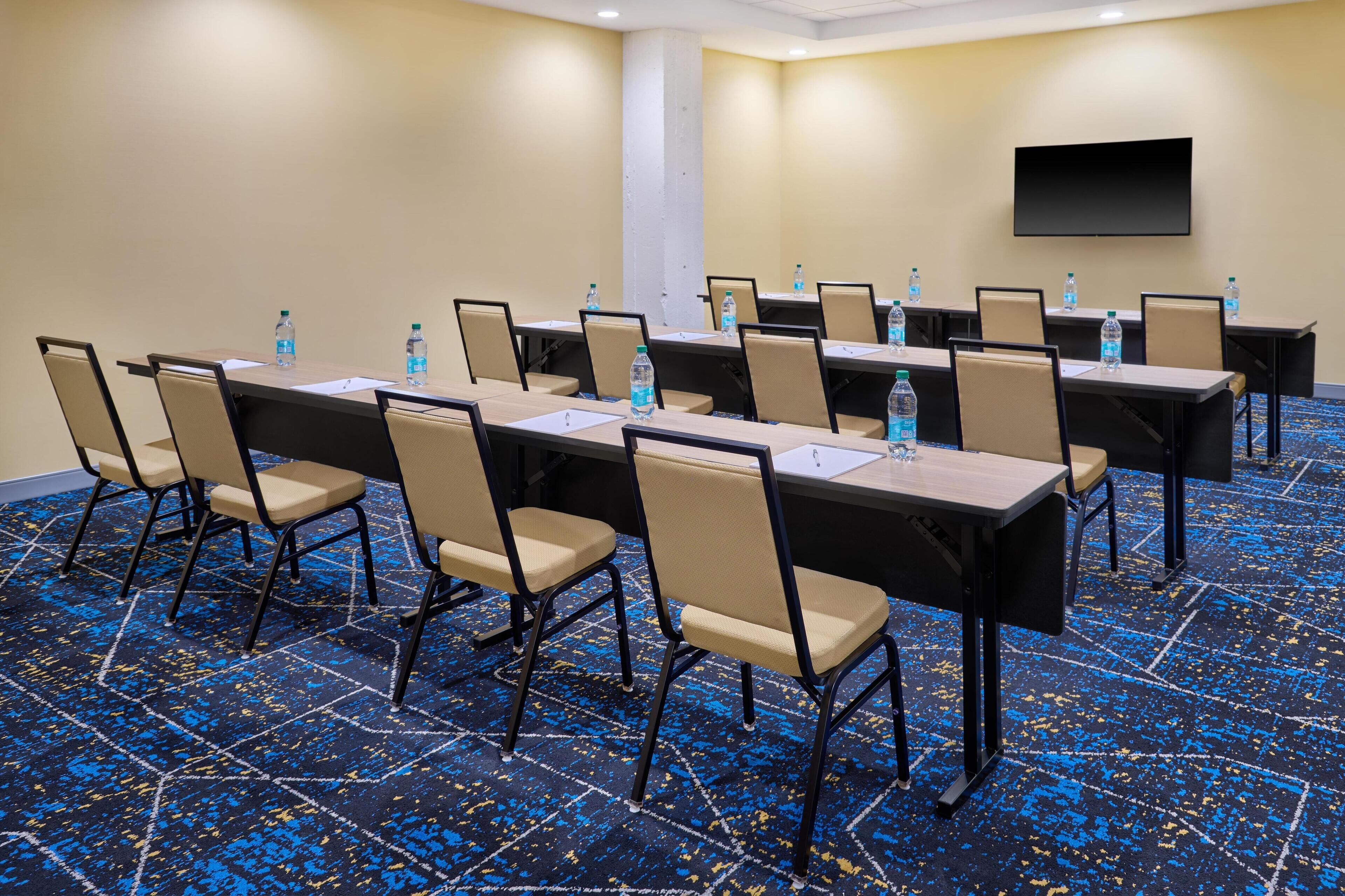 A conference room with multiple tables, chairs, and water bottles.