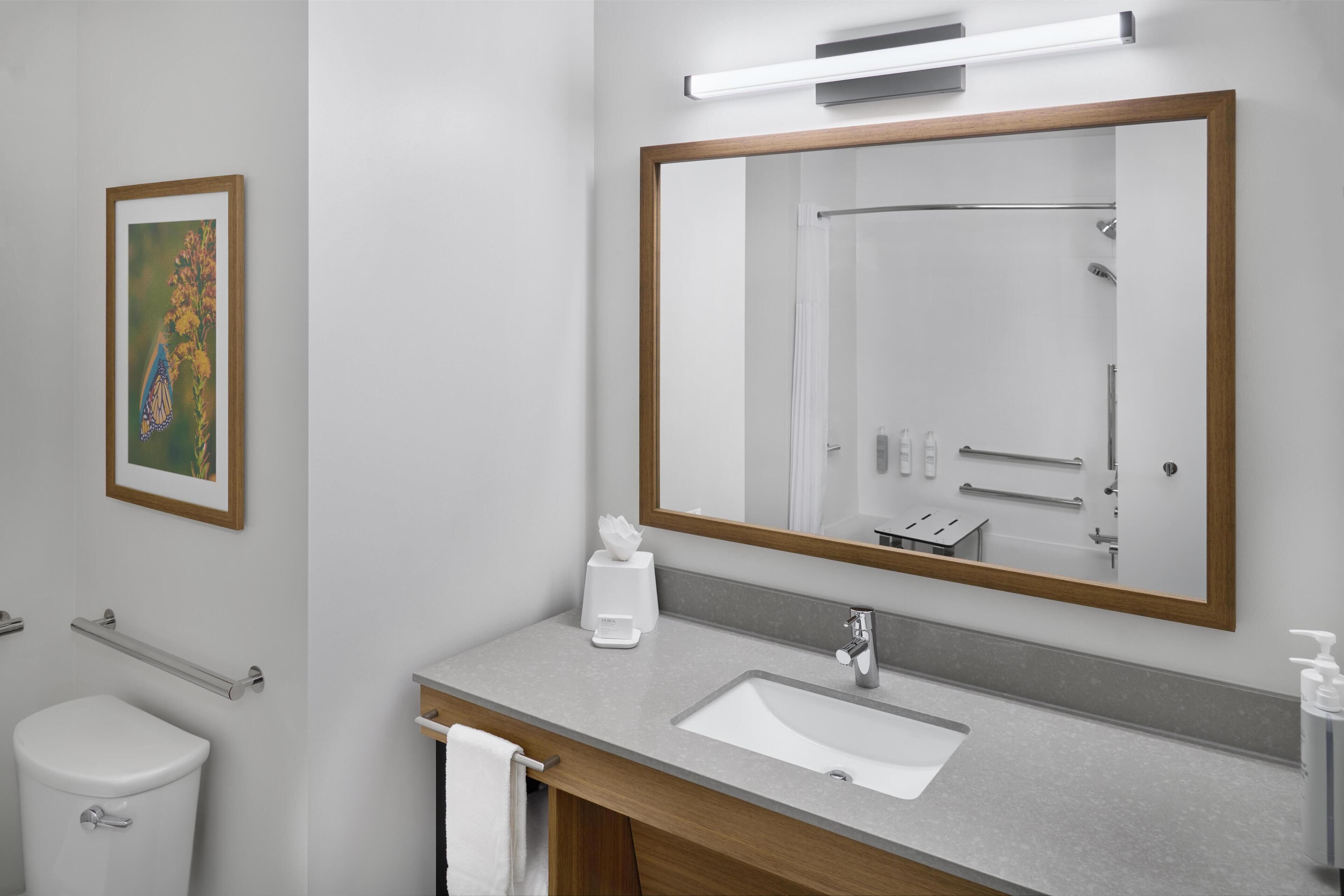 Un bagno moderno con uno specchio grande, un lavabo e un water.