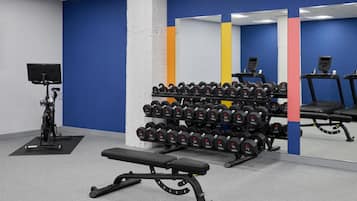 Una palestra con panche, manubri, una cyclette e un tapis roulant.