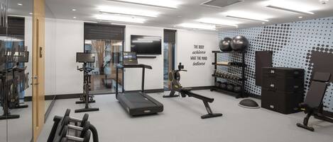 A modern gym with treadmills, weight machines, and exercise balls.