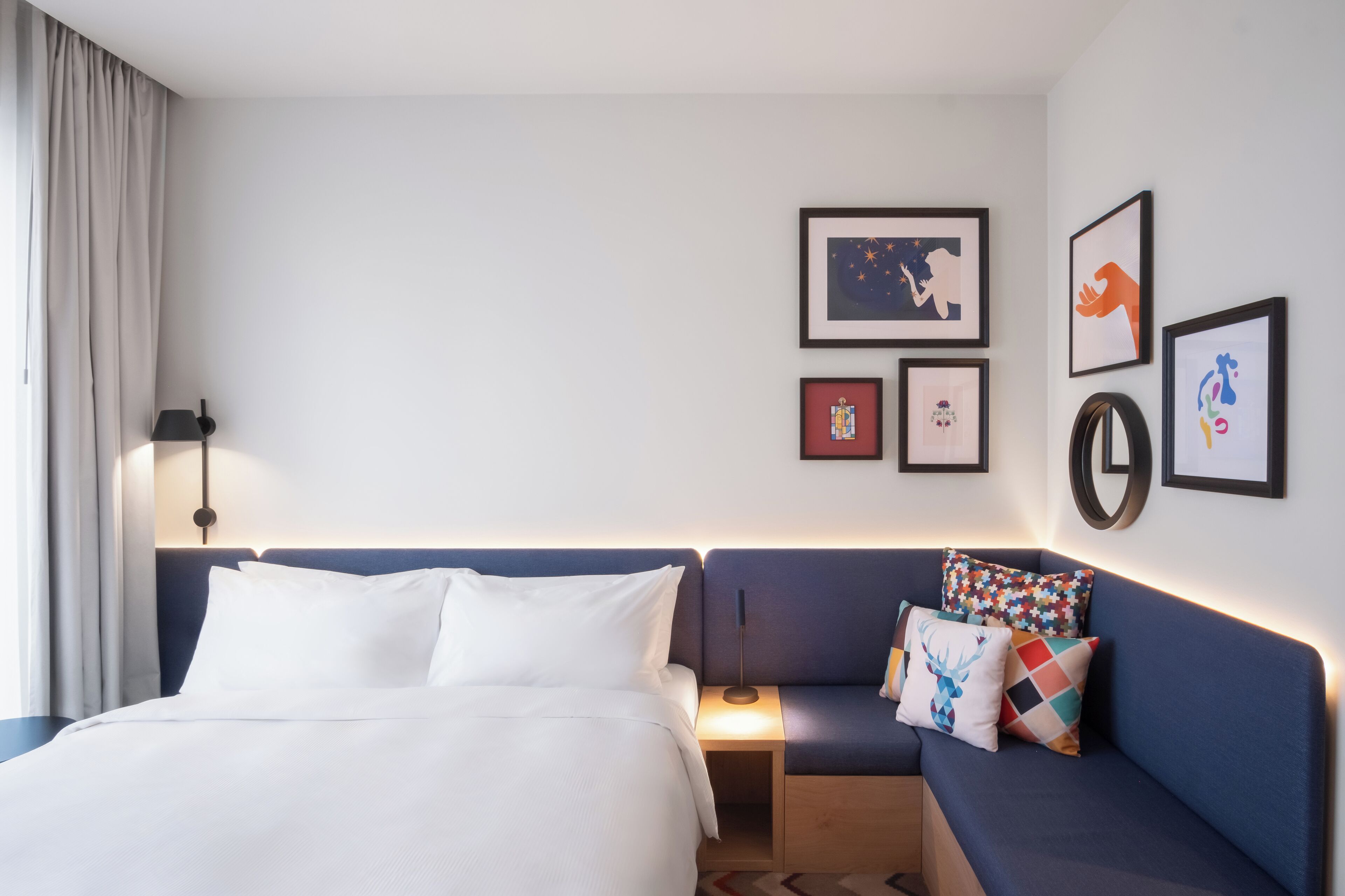 Ein Hotelzimmer mit Bett, Sofa, Nachttisch und Wandbildern.