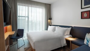 A hotel room with a bed, a desk, a chair, a sofa, and a TV. - Hampton By Hilton Tallinn (Tallinn)
