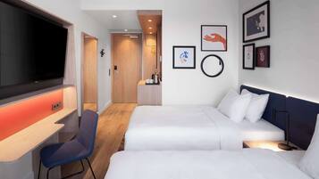 Habitació d'hotel amb dos llits, una taula de treball, un televisor i una cadira.