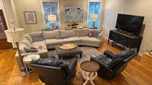 Una sala de estar con un sofá modular, dos sillones, una mesa de centro y un mueble para televisor.