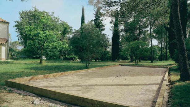 An open concrete area with a wooden border, surrounded by grass and trees. - Ahouu - Gîte with swimming pool - Pic Saint-Loup (Sauteyrargues)