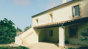 A two-story house with a covered patio, a staircase leading to the upper floor, and a small garden area. - Ahouu - Gîte with swimming pool - Pic Saint-Loup (Sauteyrargues)