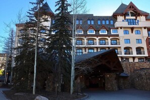 A multi-story hotel with a stone facade, large windows, and a prominent entrance with a wooden structure. - Luxury Hotel Room With 2 Queen Beds in Lionshead Village (Vail)