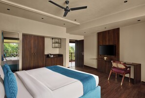Une chambre d’hôtel moderne équipée d’un lit, d’un bureau, d’une télévision et d’un balcon.