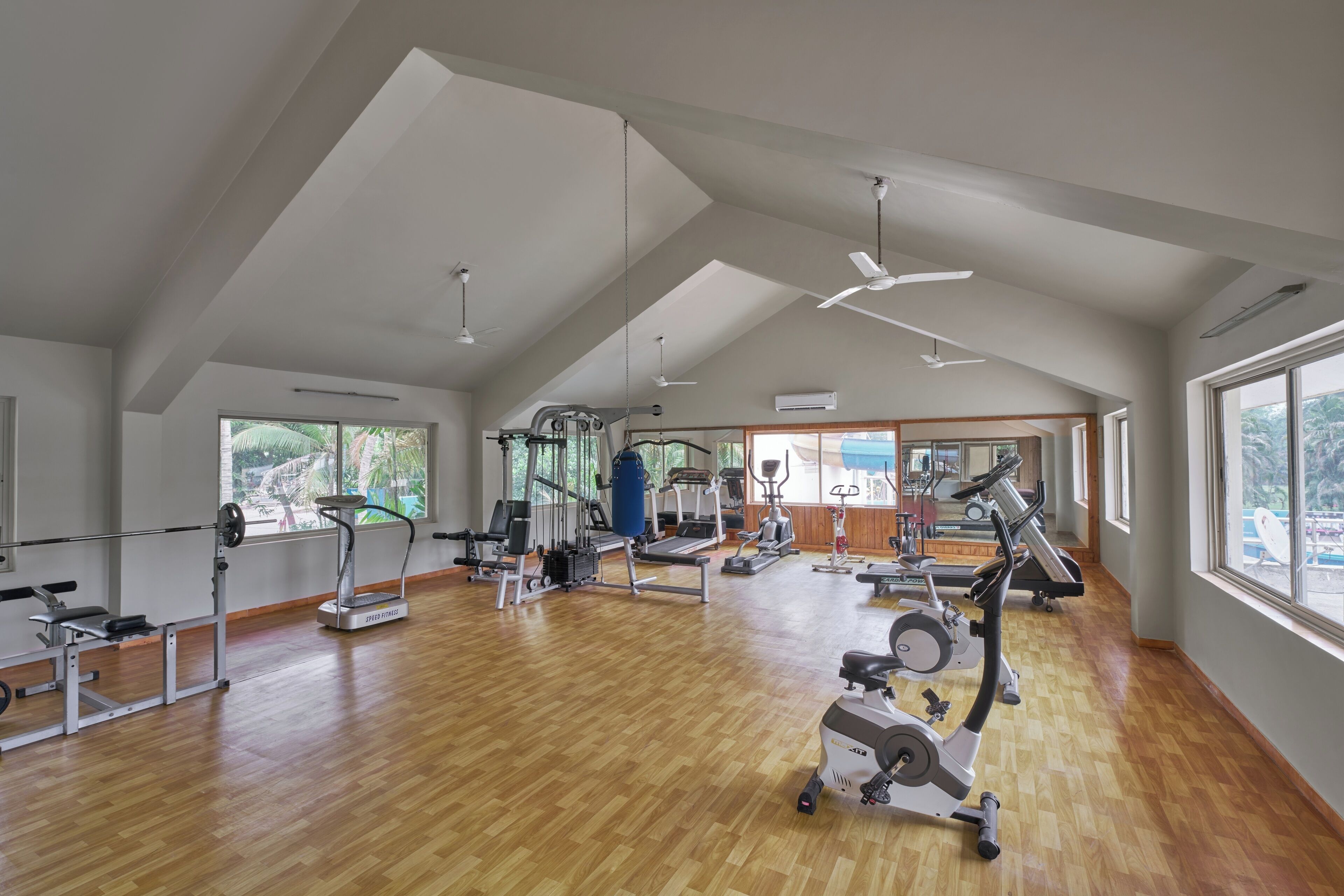 Un gimnasio amplio con diverso equipo de ejercicio, ventanas grandes y techos altos.