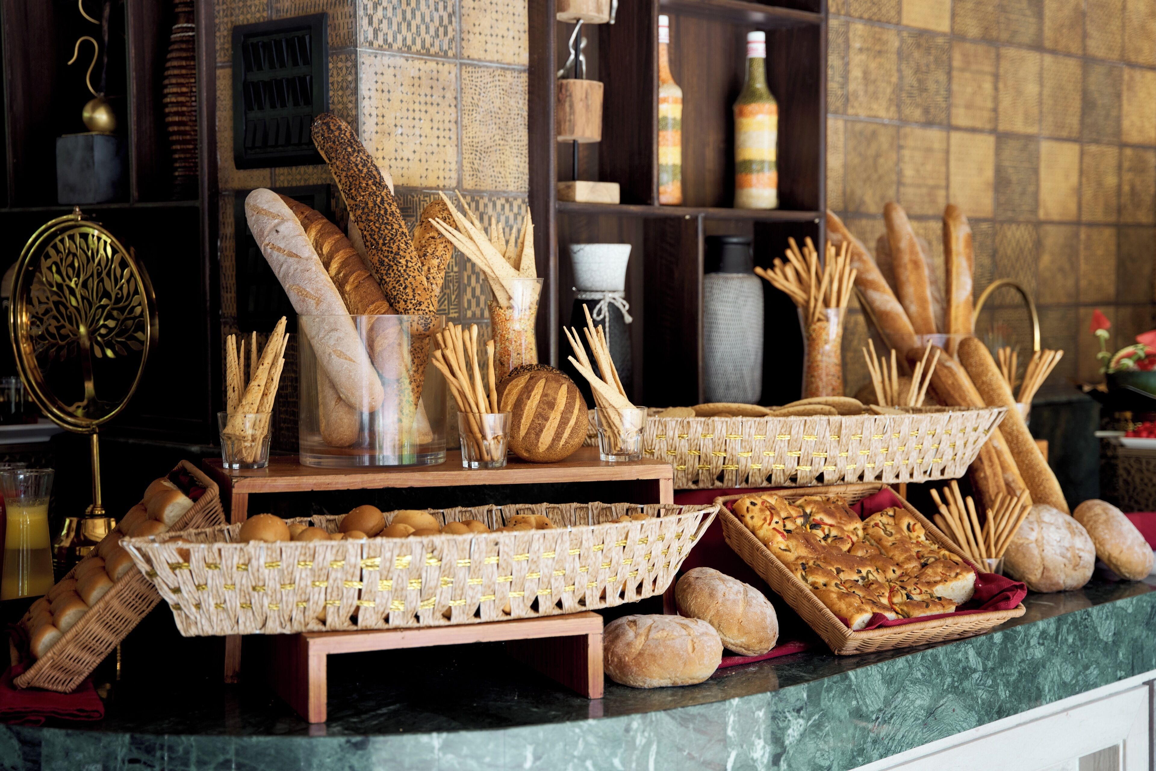 A variety of breads and pastries displayed on a counter with baskets and a decorative mirror.