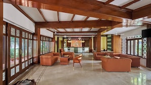 A spacious lobby with wooden beams, a reception desk, and seating areas. - DGV Resort by Treat, Silvassa (Silvassa)