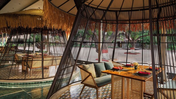 A restaurant with a curved ceiling, bamboo walls, and a central seating area with a table and chairs. - DGV Resort by Treat, Silvassa (Silvassa)