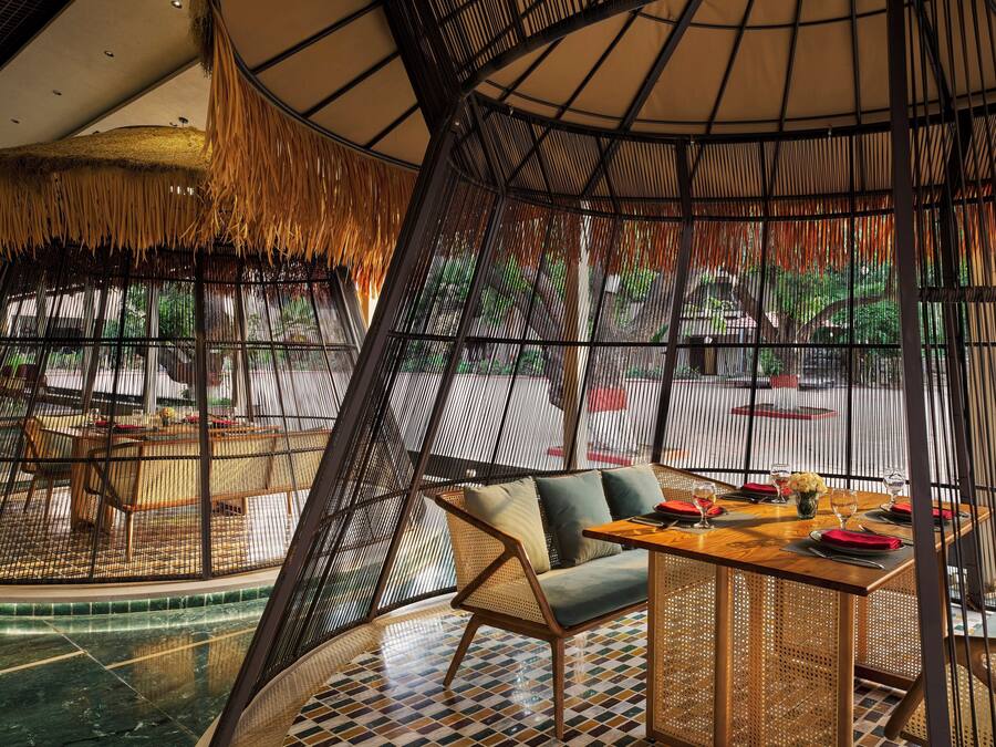 A restaurant with a curved ceiling, bamboo walls, and a central seating area with a table and chairs.