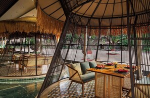 A restaurant with a curved ceiling, bamboo walls, and a central seating area with a table and chairs. - DGV Resort by Treat, Silvassa (Silvassa)