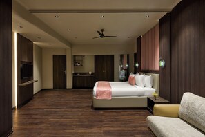Une chambre d’hôtel moderne dotée d’un grand lit, d’un coin salon, d’une télévision et d’une salle de bain.