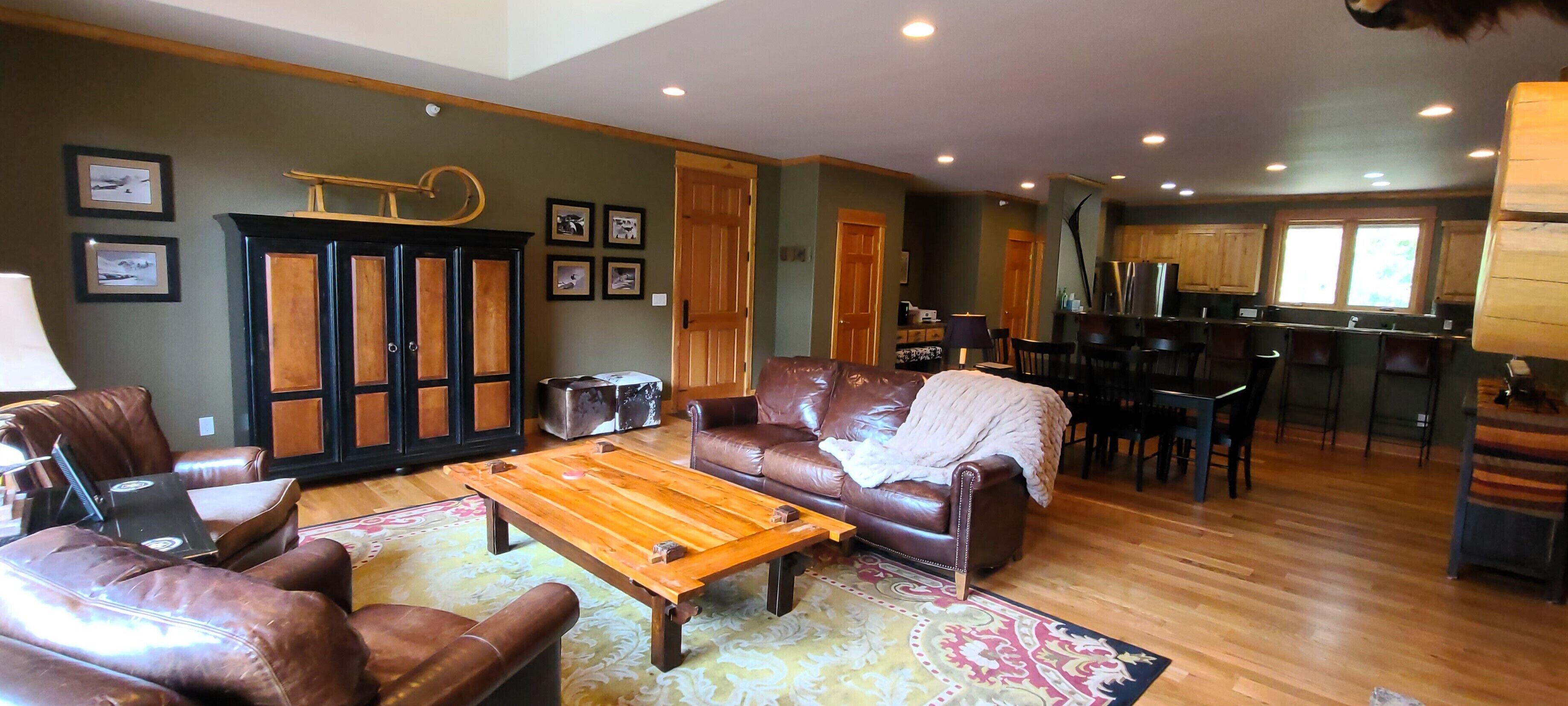 A spacious living room with leather furniture, a wooden coffee table, and a patterned rug.