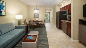 A hotel room with a sofa, a coffee table, a dining table with chairs, a kitchen area with a refrigerator, microwave, and cabinets. - Charming 2-bedroom apartment with AC, WiFi in pleasant Orlando (Orlando)