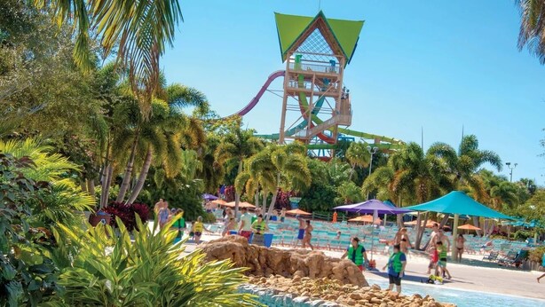 A water park with a large water slide, palm trees, and a pool area with umbrellas. - Charming 2-bedroom apartment with AC, WiFi in pleasant Orlando (Orlando)