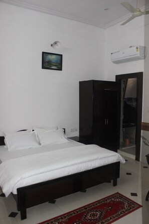 A bedroom with a bed, a wardrobe, a mirror, and a ceiling fan. - hotel lasani inn (Udaipur)