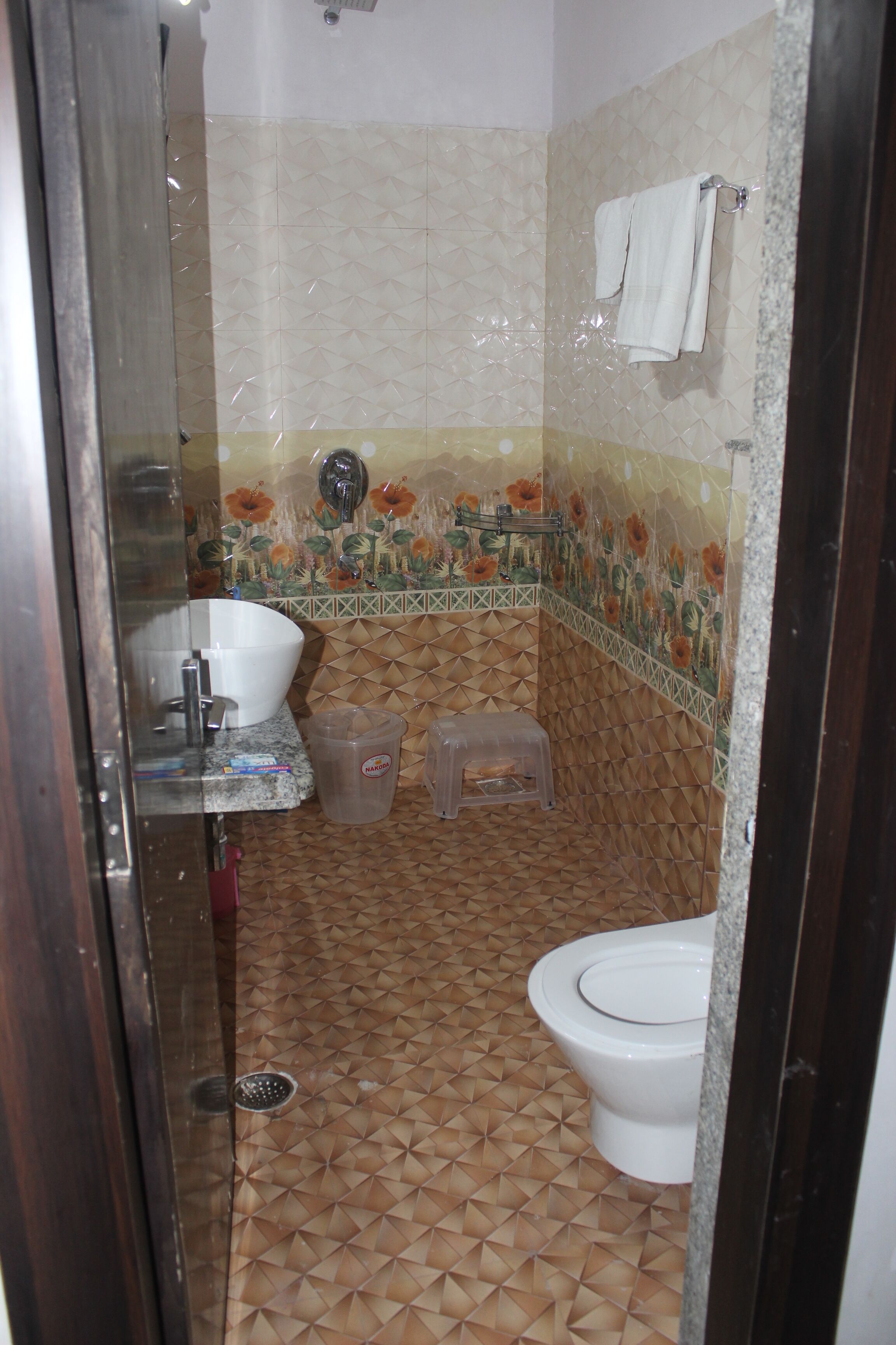 A bathroom with a tiled floor, a sink, a toilet, and a shower area.