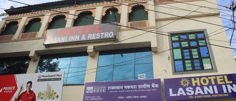 A hotel named 'Hotel Lasani Inn & Restro' with a signboard advertising 'FlowGuard Plus' plumbing systems and 'Prince Pipes'.
