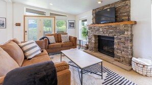 A living room with a stone fireplace, a sofa, and a television. - Ski Winter Park/ Granby Ranch-Hot Tub- Pets-Sled- Multi-Family House (Granby)