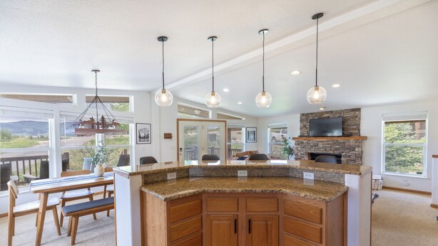 A modern kitchen with granite countertops, wooden cabinets, and a stone fireplace. - Ski Winter Park/ Granby Ranch-Hot Tub- Pets-Sled- Multi-Family House (Granby)