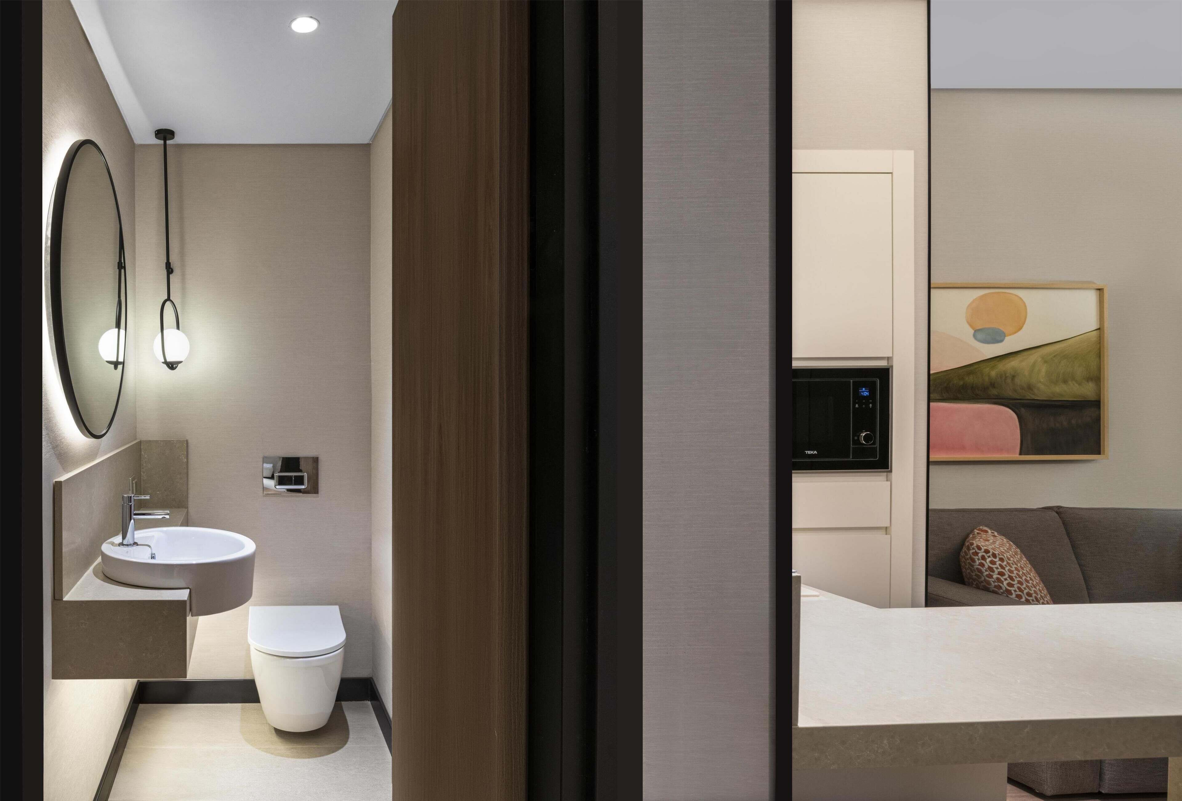 A modern bathroom with a sink, toilet, and mirror.