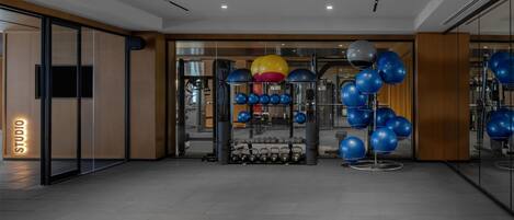 A modern gym with exercise equipment, a mirrored wall, and a 'STUDIO' sign.