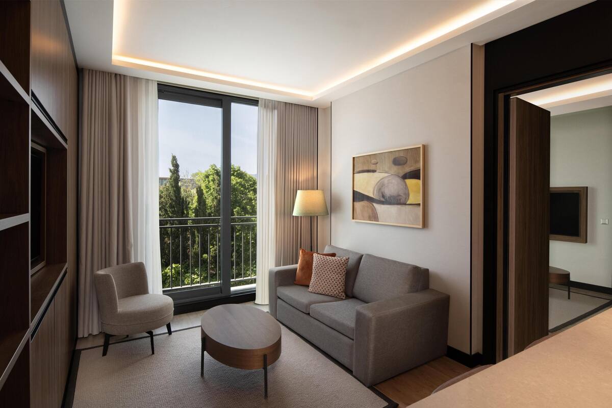 A modern hotel room with a sofa, armchair, and a small table.