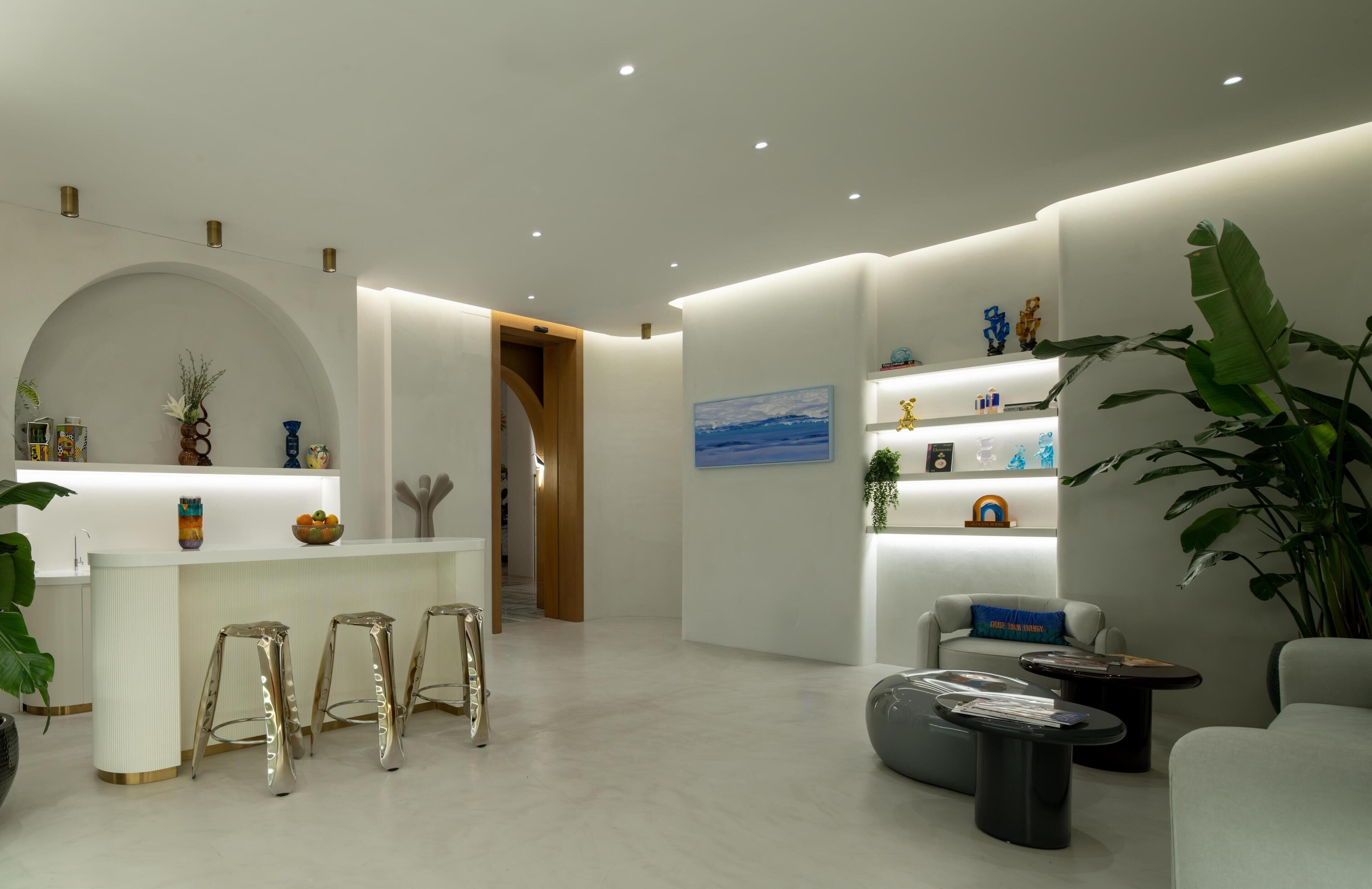 A modern interior with a reception desk, bar stools, seating area, and decorative elements.