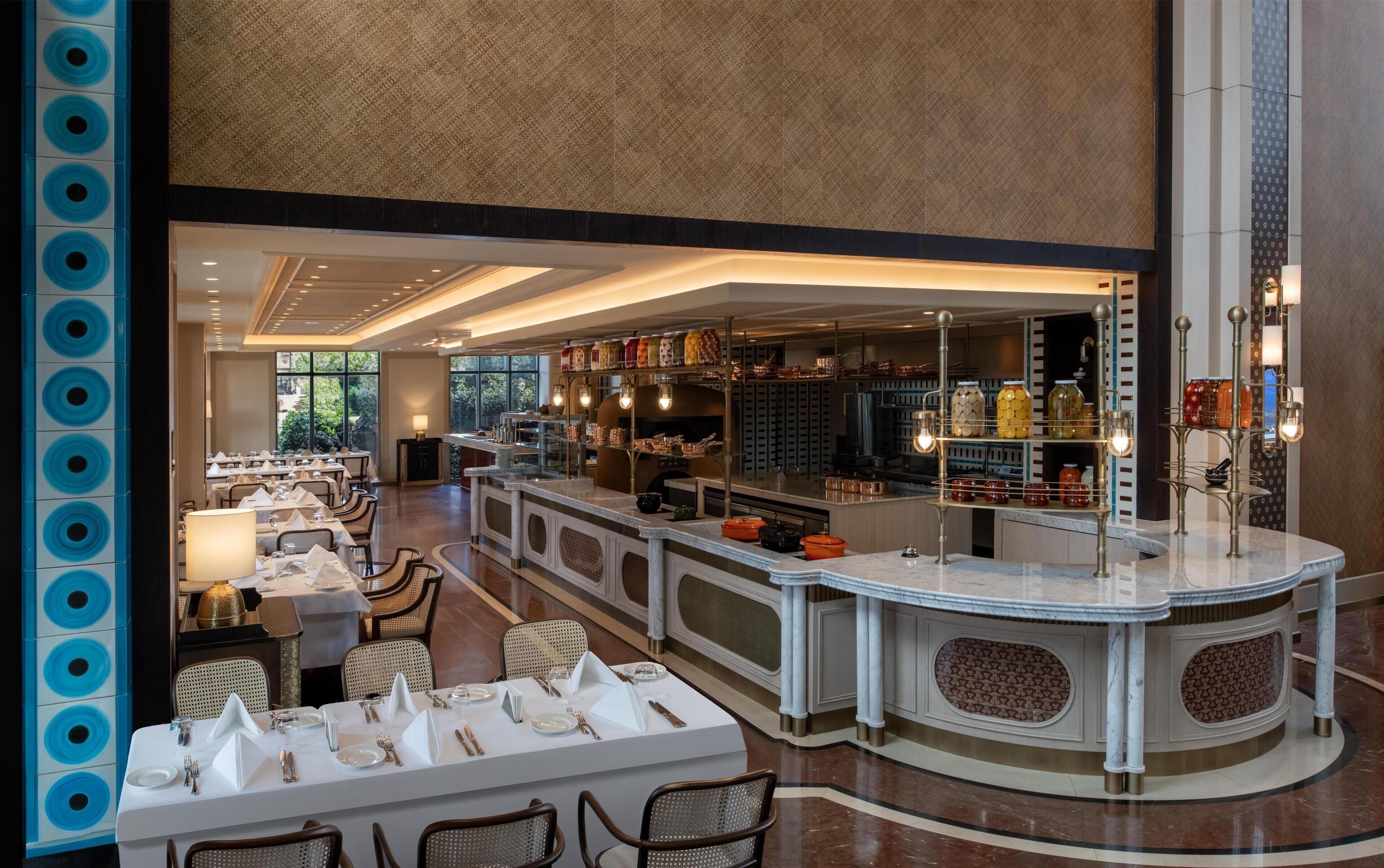 A spacious hotel lobby with a central bar area, seating arrangements, and a view of the outdoors.